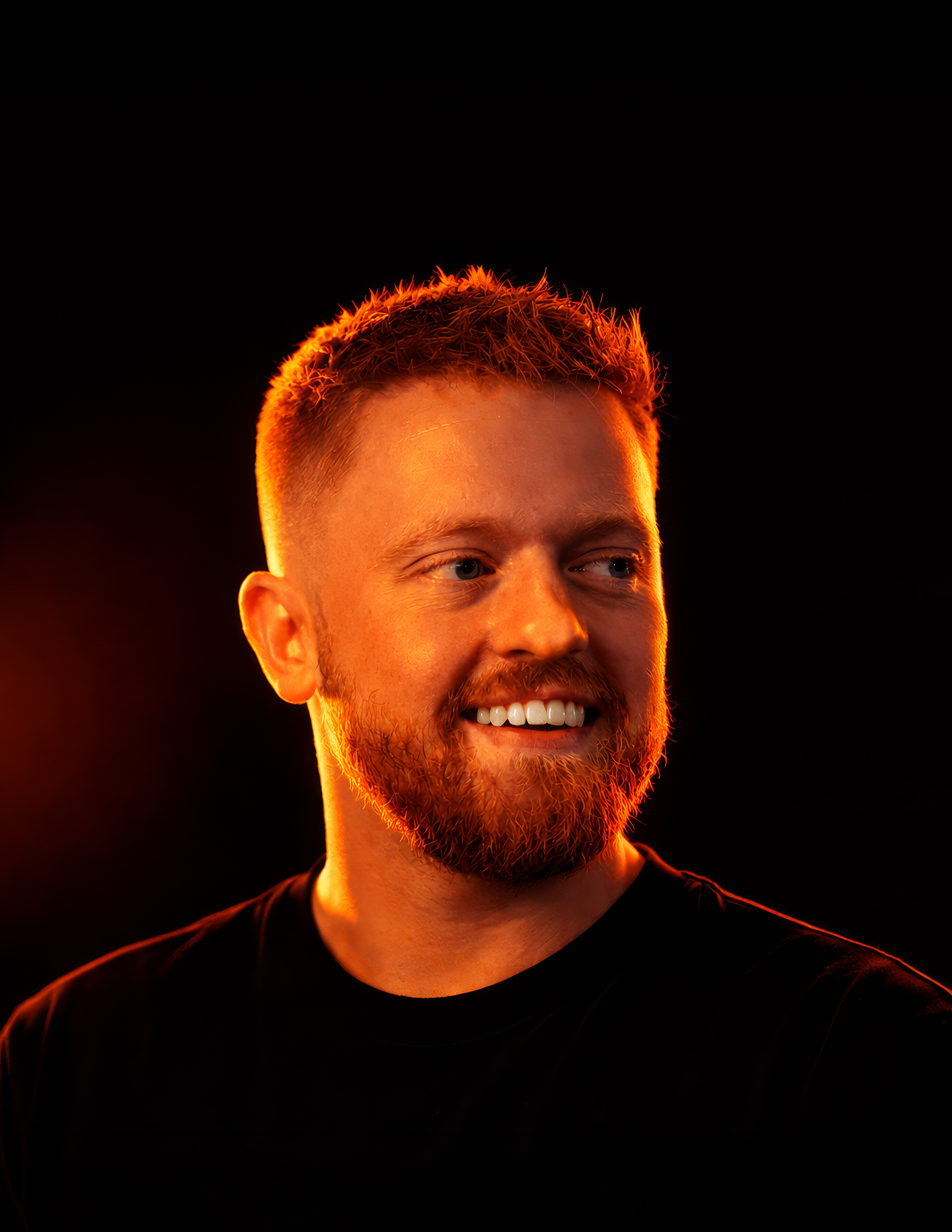 Portrait of Ryan Elliott, ember-lit on a dark backdrop